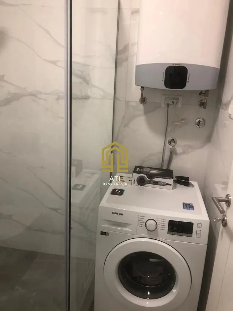 Small bathroom with a washing machine, water heater, and shower cabin.