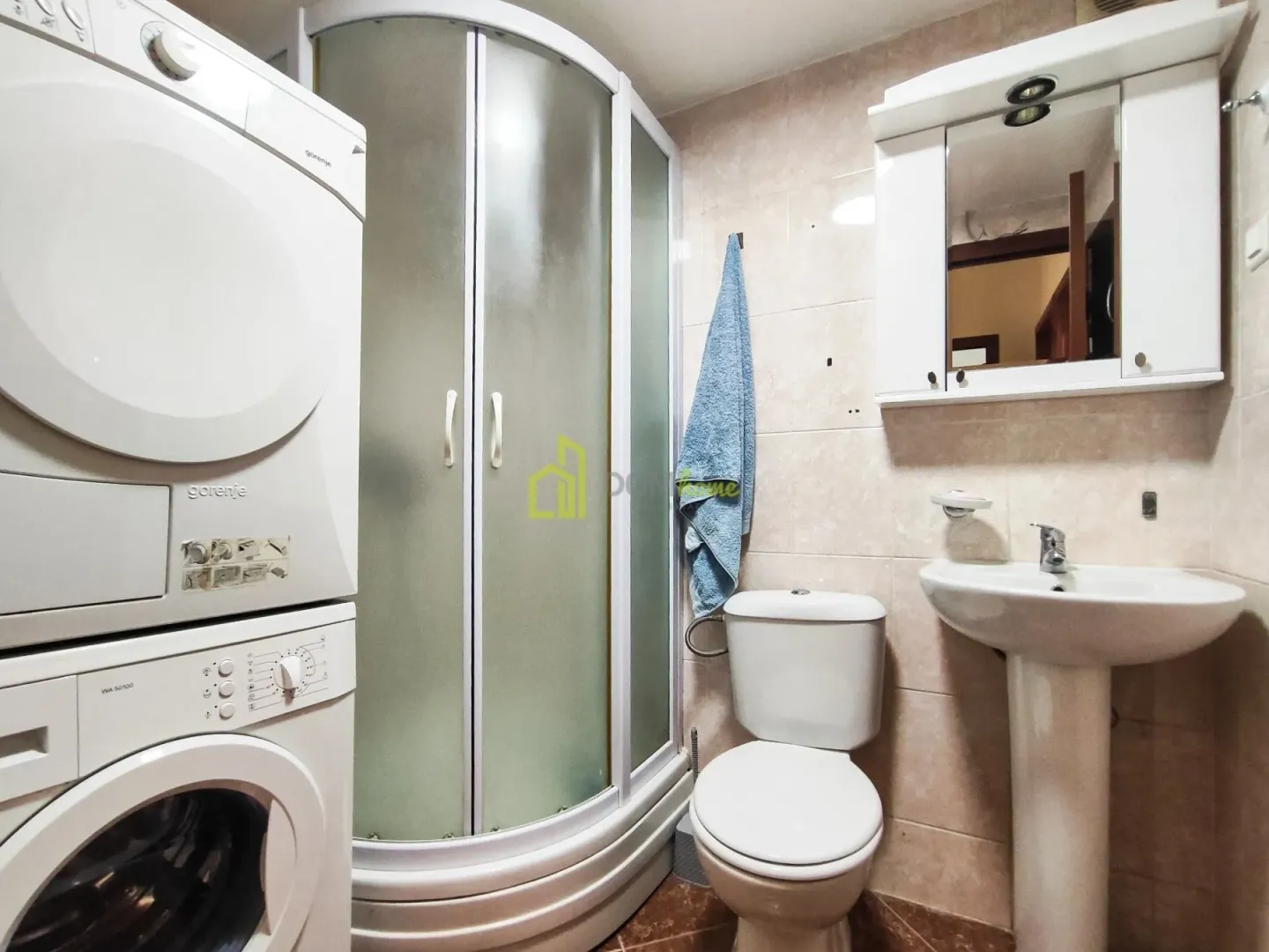 Bathroom equipped with a shower cabin, washbasin, toilet, and washing machine.