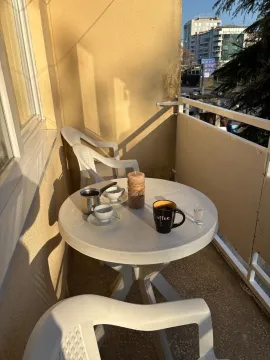 A sunlit balcony featuring a round plastic table and chairs. - image 19