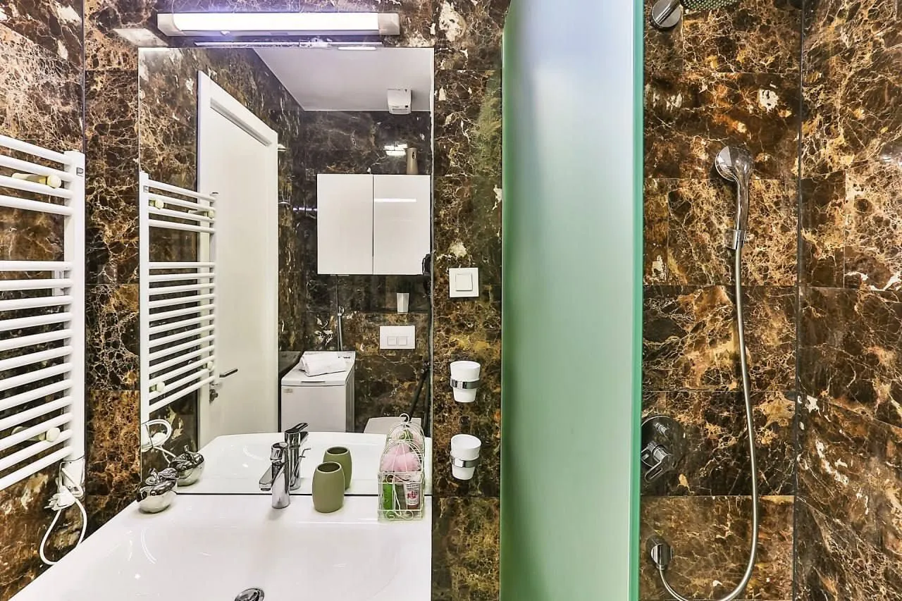 Modern bathroom with a sink, shower cabin, and marble tiles.