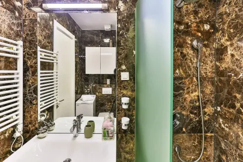 Modern bathroom with a sink, shower cabin, and marble tiles. - image 8
