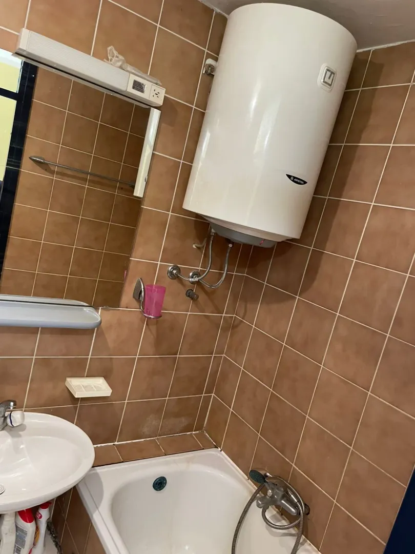 Bathroom with a bathtub, washbasin, mirror, and water heater.