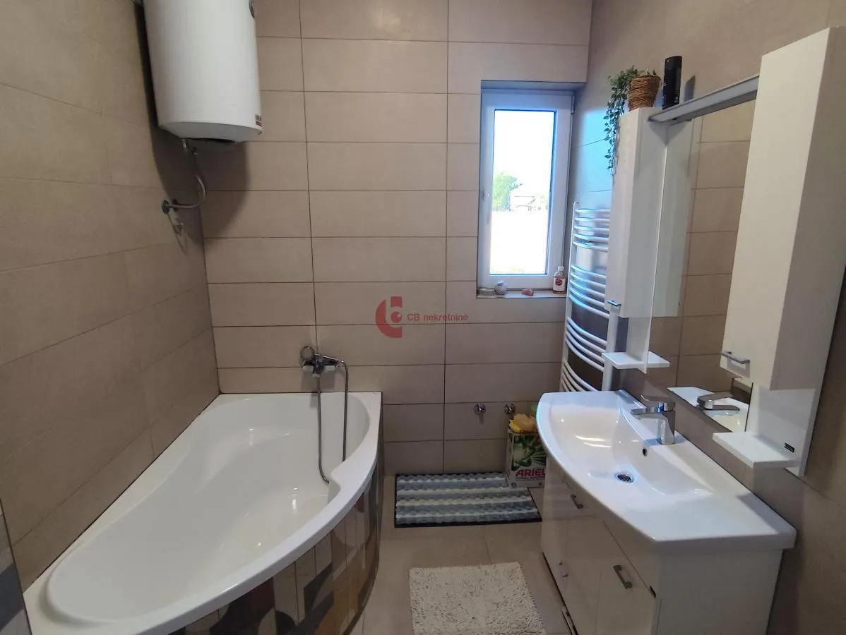 Small bathroom with bathtub, washbasin, and water heater.