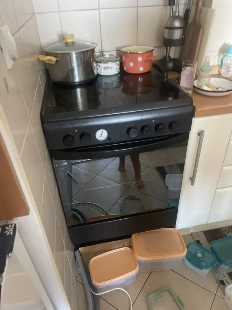 A view of the stove and part of the kitchen with dishes.