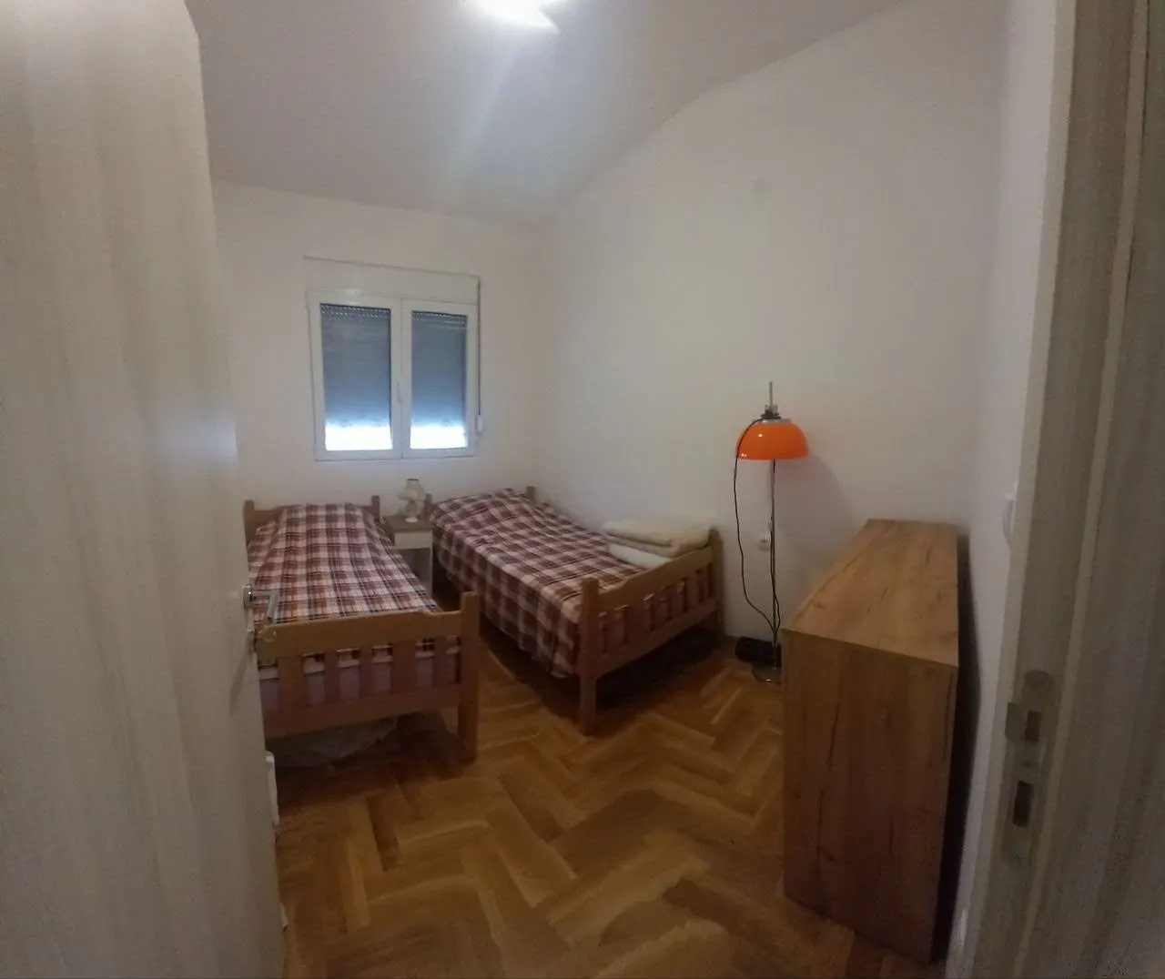 Smaller bedroom with two wooden beds and parquet flooring.