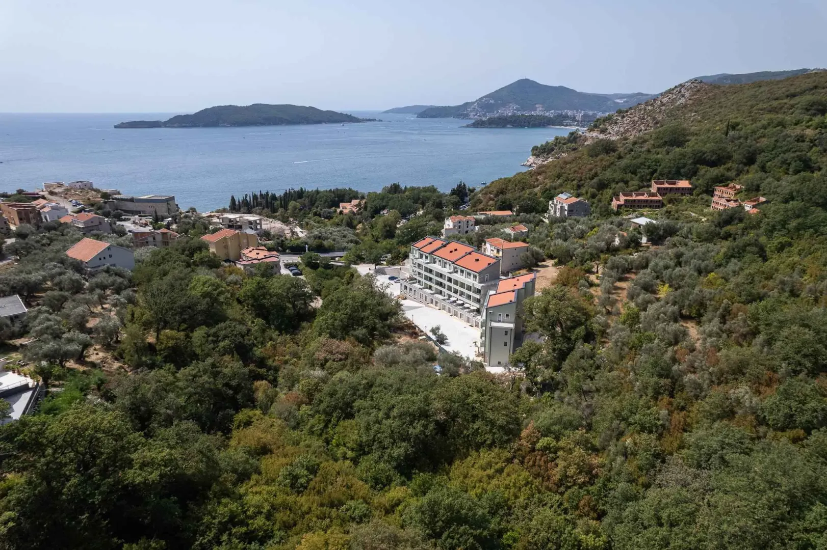 Pogled iz vazduha na kompleks zgrada okružen zelenilom sa pogledom na more.
