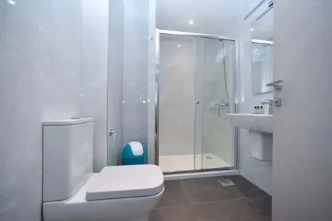 Modernly equipped bathroom with a shower cabin, toilet, and sink. - image 3