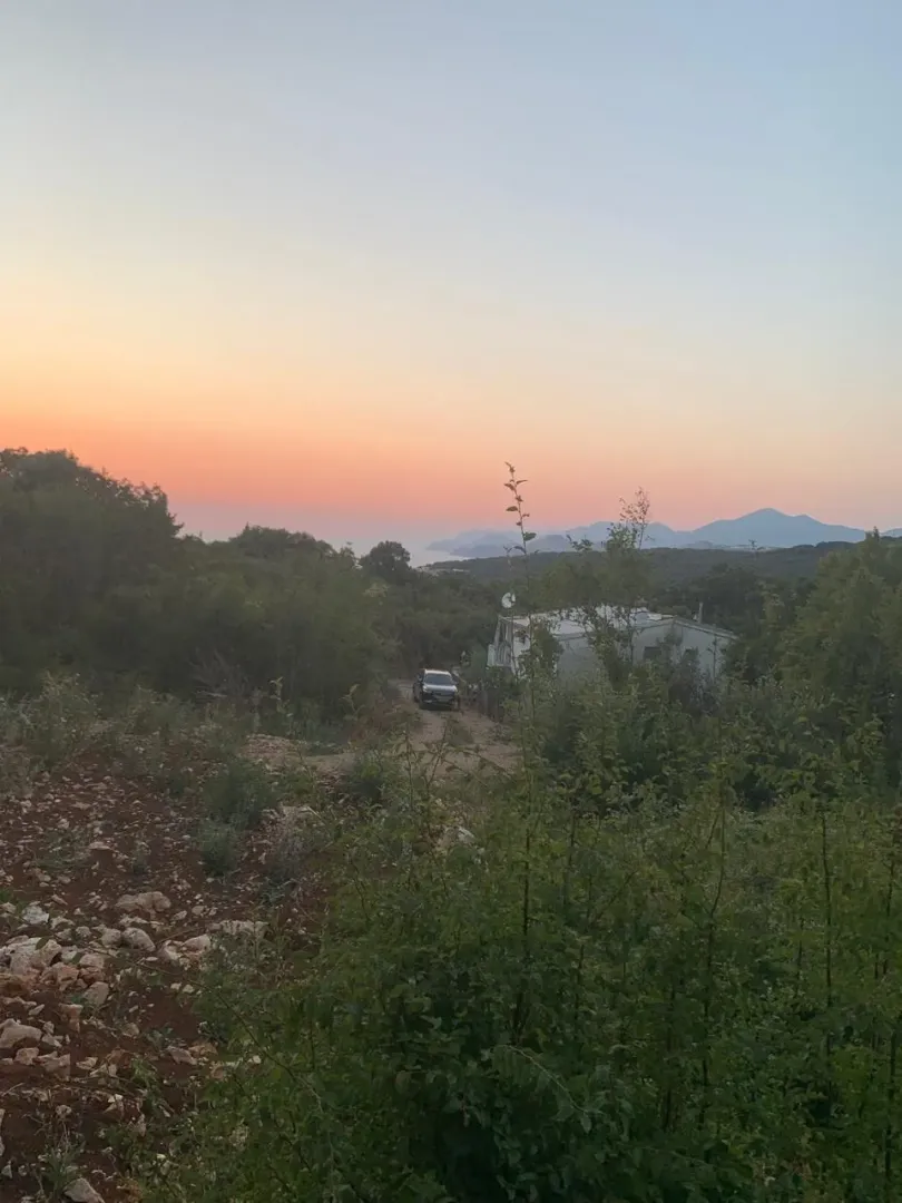 Pogled na kuću i okolno zelenilo u sumrak.
