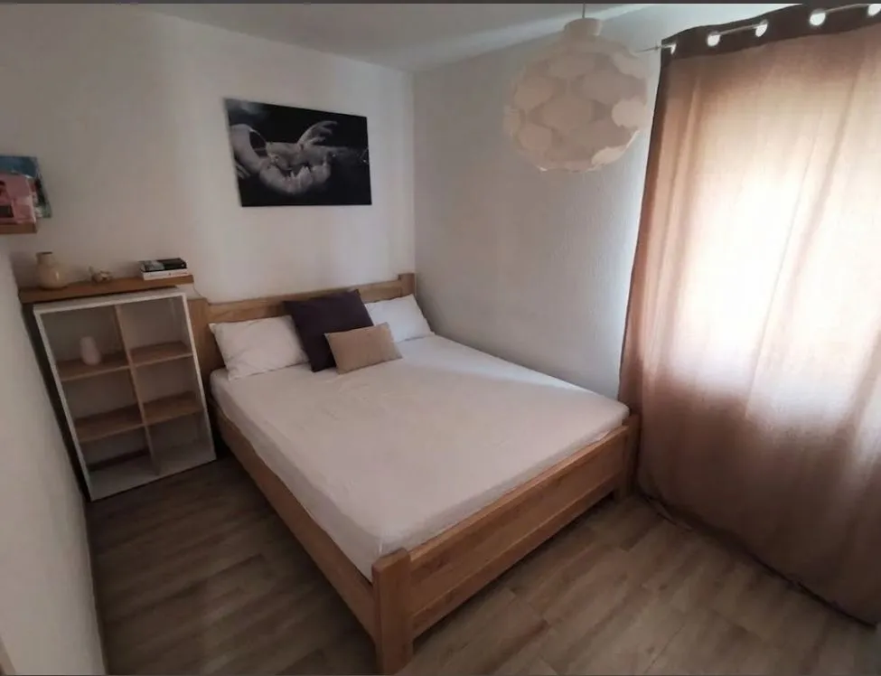 Furnished bedroom with a double bed, shelf, and window.