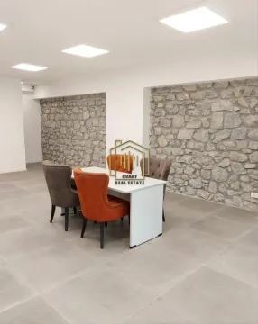 Dining table with chairs in a spacious room featuring a decorative stone wall. - image 2