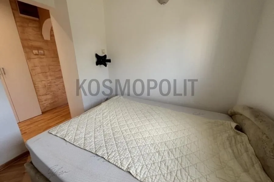 Manja spavaća soba sa krevetom i pogledom prema hodniku.