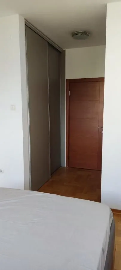 Pogled na spavaću sobu sa ugradnim ormarom i vratima.