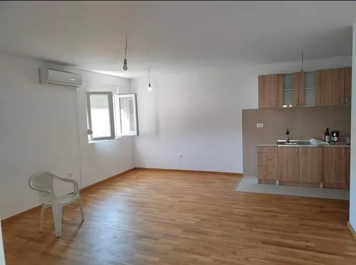 Living room with kitchen and parquet flooring.