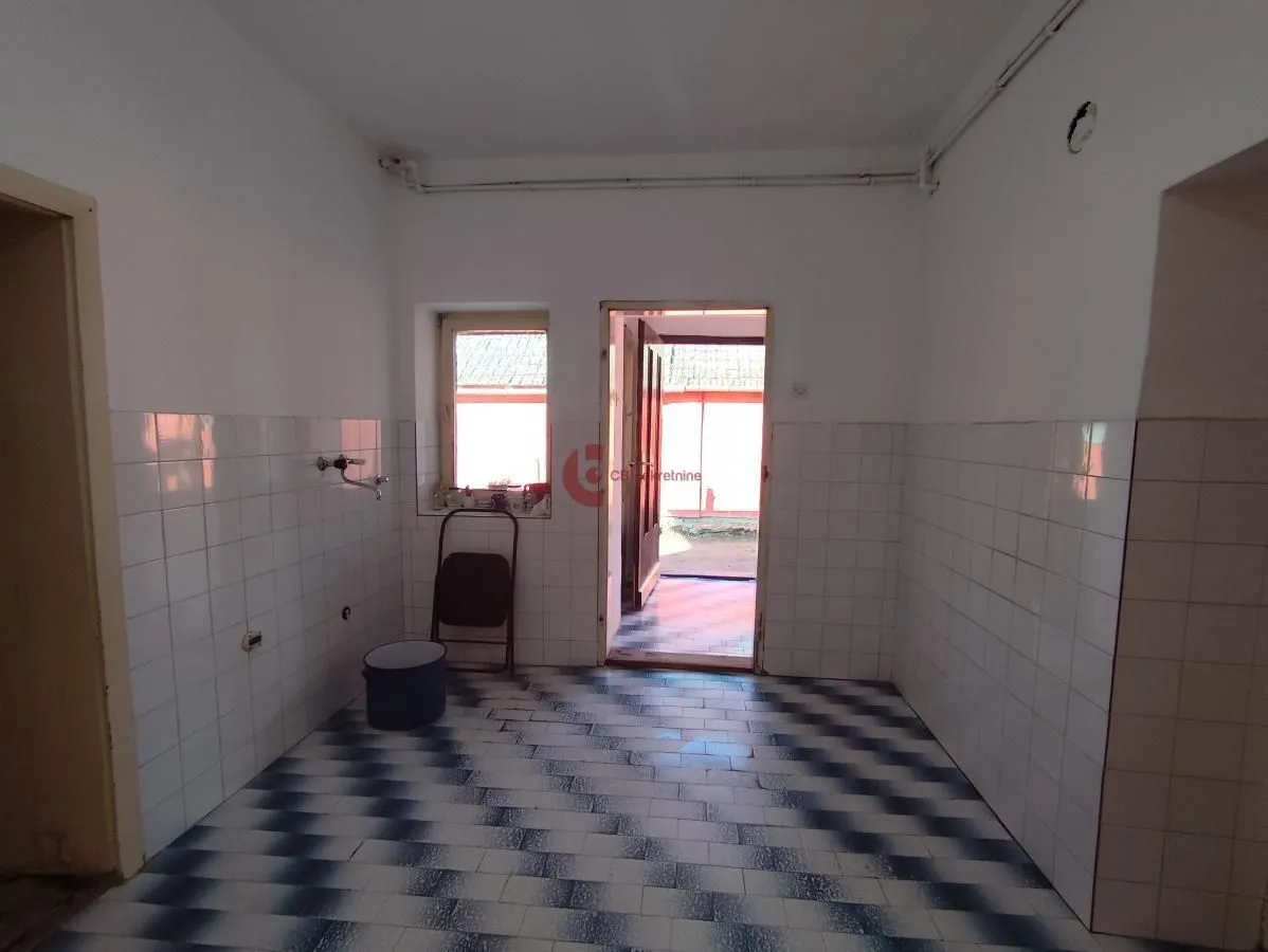 Prazna kuhinja sa pločicama na zidovima i podu i izlazom napolje.