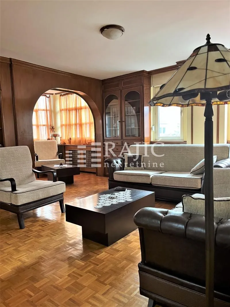 Living room with seating furniture, wooden elements and parquet flooring.