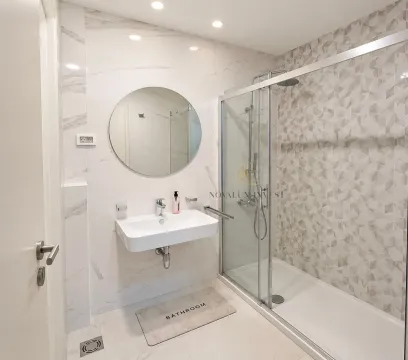 Moderne kupatilo sa tuš kabinom, umivaonikom i okruglim ogledalom. - image 6