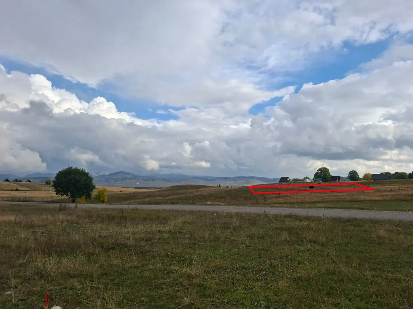 Pogled na zemljište sa ucrtanim crvenim okvirom i prirodu u pozadini.