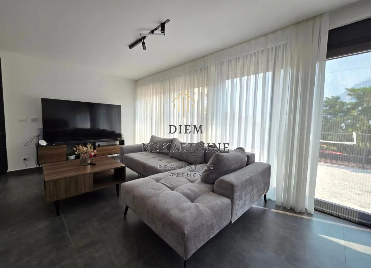 Modern living room with a sofa and large windows.