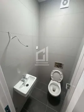 Manje kupatilo sa umivaonikom i šoljom obloženo sivim pločicama. - image 4