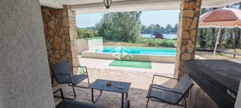 Covered terrace with seating furniture and a view of the pool and the river. - image 36