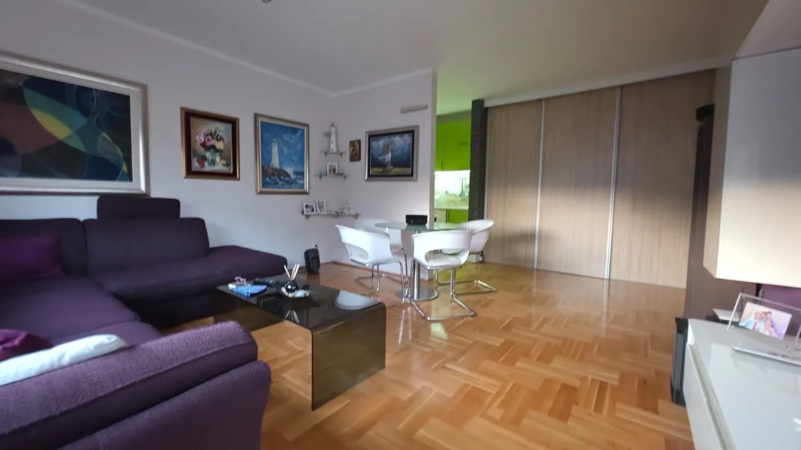 Living room with a sofa set, dining table and parquet flooring.