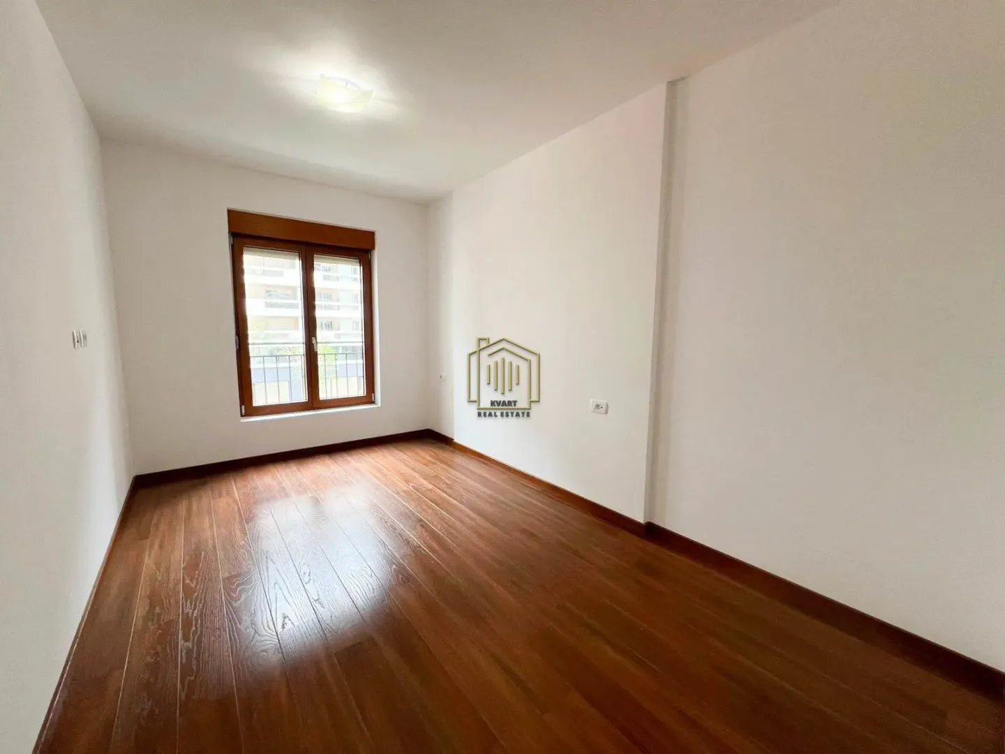Empty room with wooden flooring and a window.