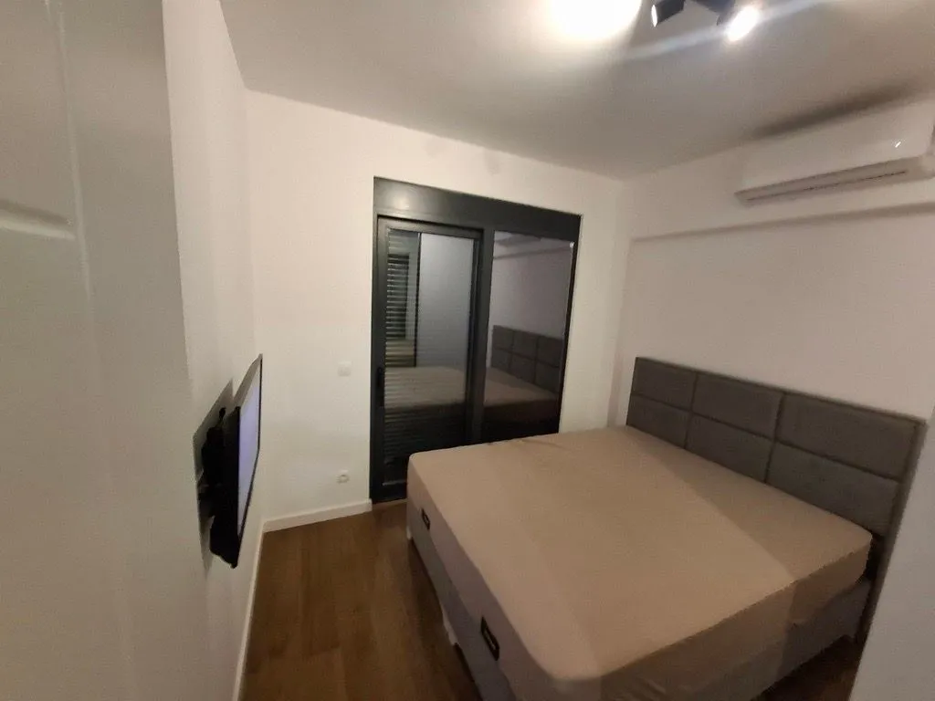 Furnished bedroom with a double bed, TV, and air conditioning.
