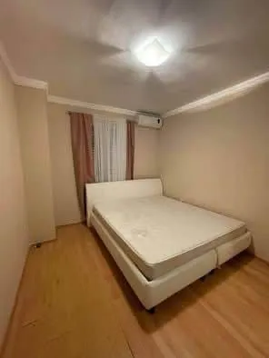Spavaća soba sa bračnim krevetom, drvenim podom i prozorom sa zavjesama.