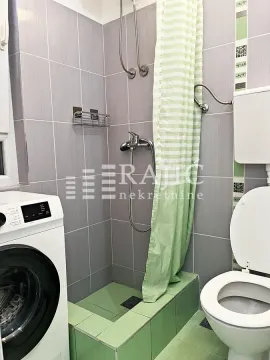Smaller bathroom with a shower enclosure, toilet, and washing machine. - image 4