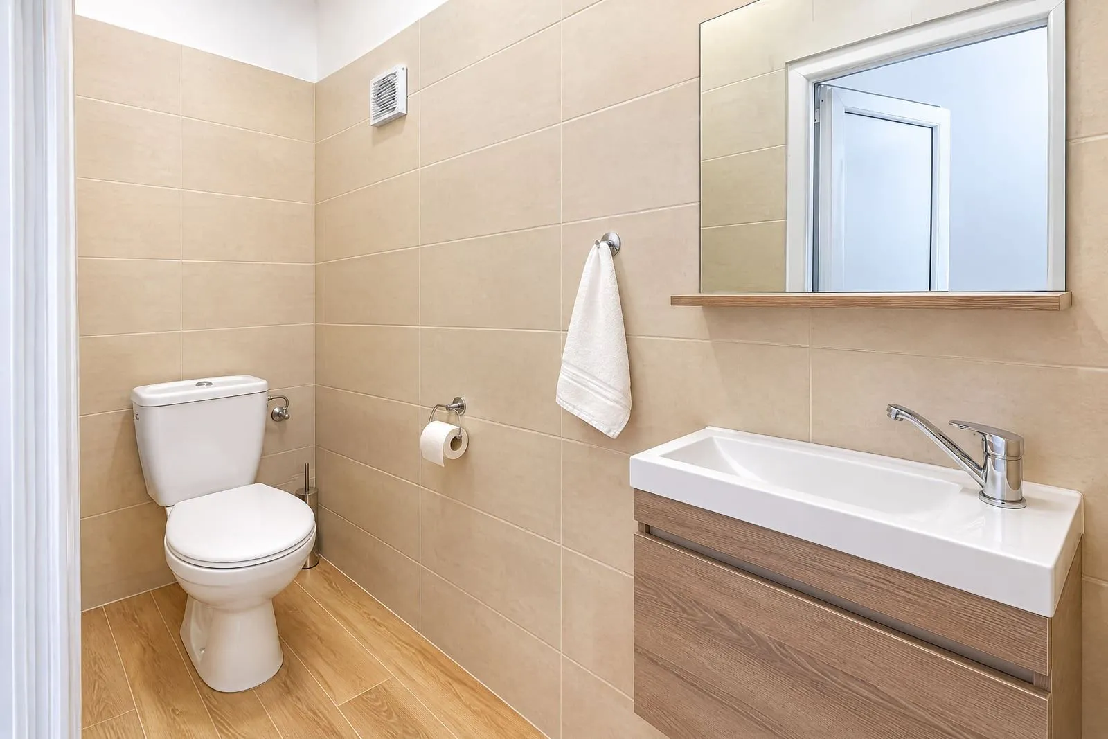 Small bathroom with a toilet, washbasin, and mirror.
