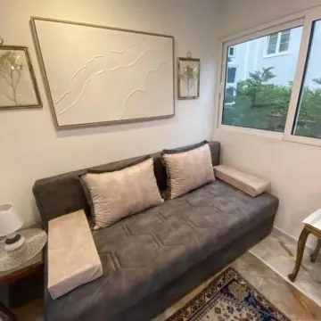 Small living room with a grey sofa and decorative paintings on the wall. - image 5