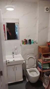 Kupatilo sa bijelim pločicama mermerne teksture, lavaboom i toaletom. - image 8