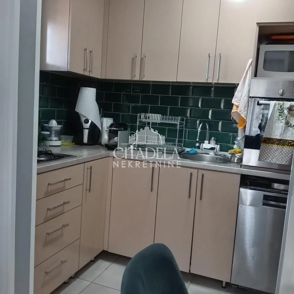 Manja opremljena kuhinja sa gornjim i donjim elementima i ugradnim uređajima.