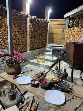 Natkriveni dio dvorišta sa roštiljem, stolom i uredno složenim drvima. - image 3