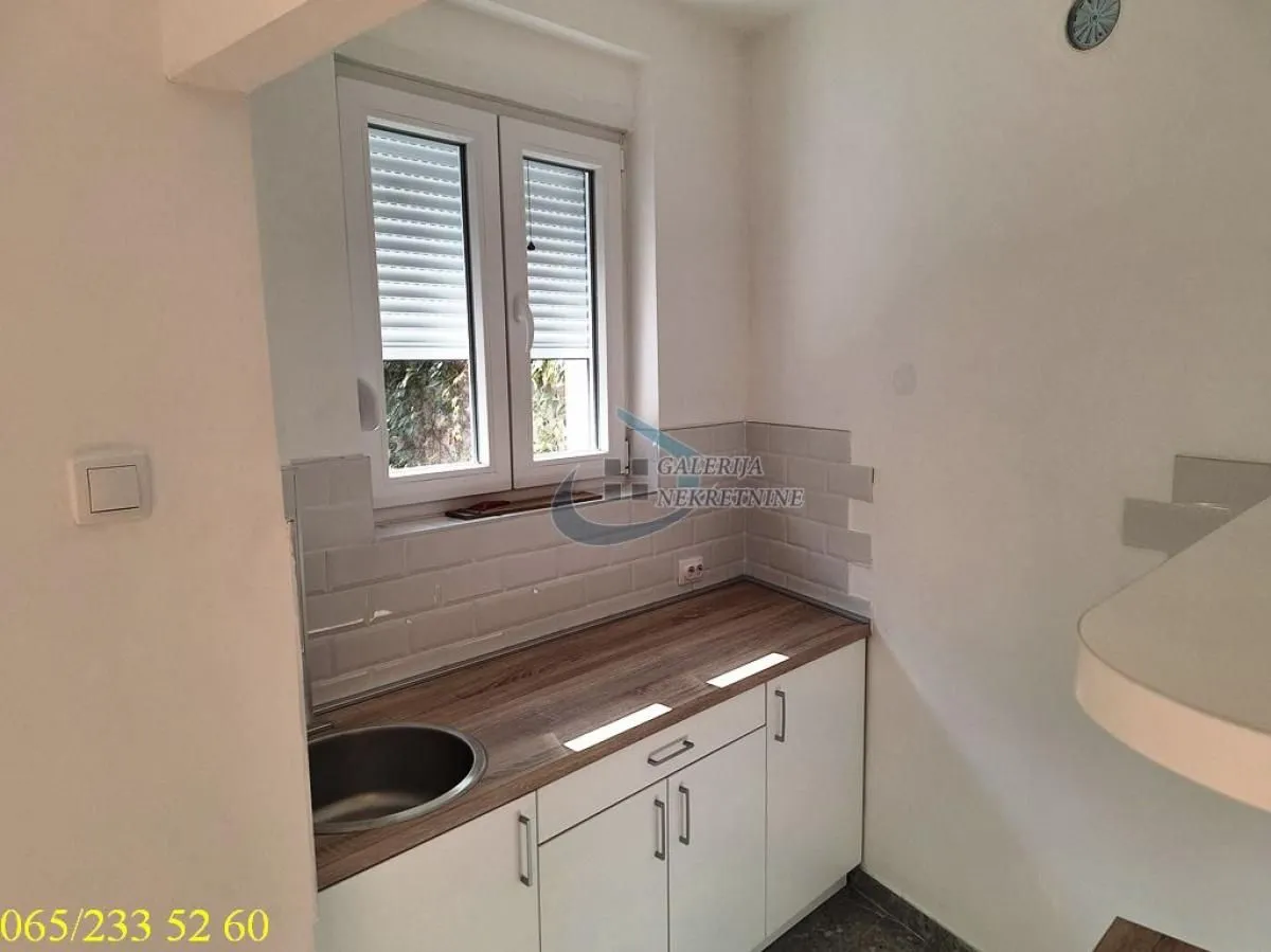Small kitchen with white units and a window.