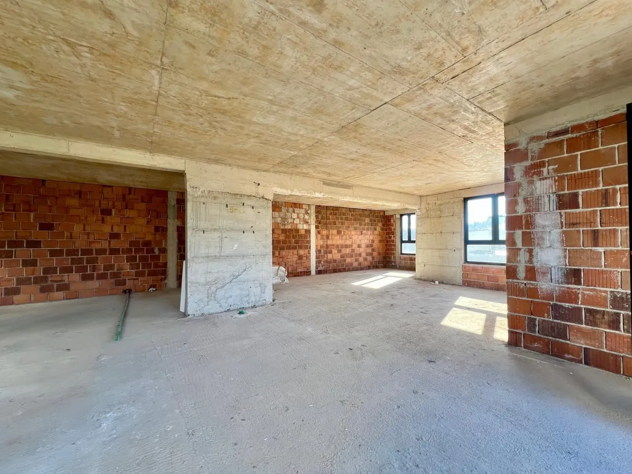 Interior of an unfinished space in grey construction phase with an open layout.