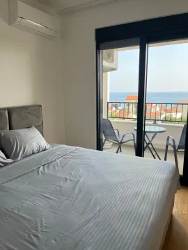 Bedroom with a double bed and a sea view through the balcony door. - image 12