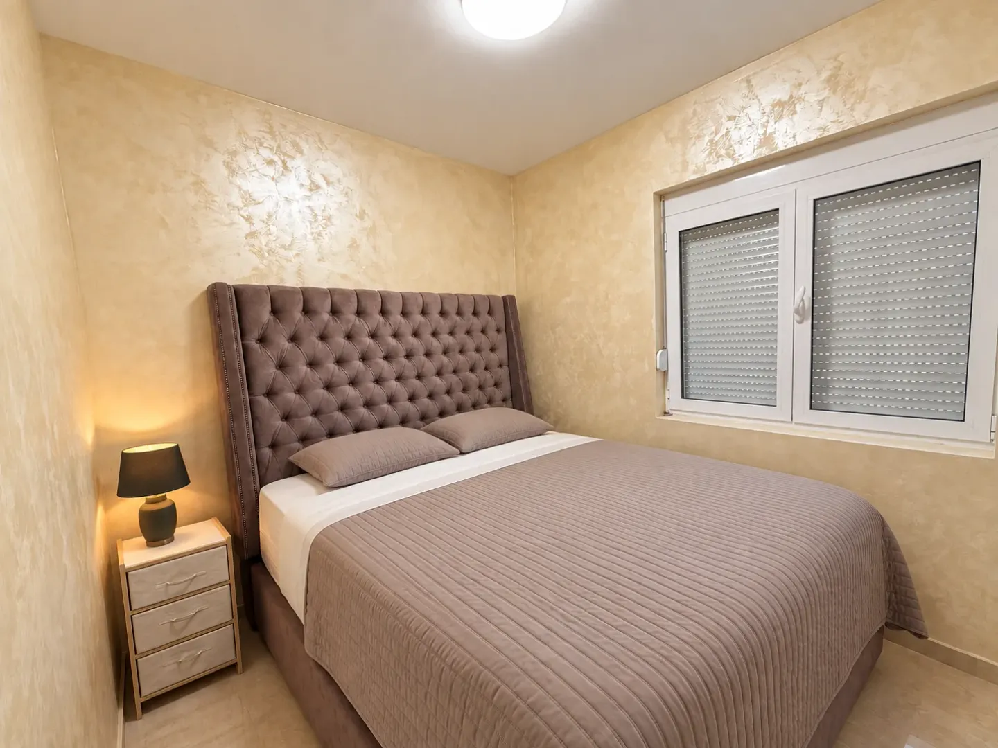 Furnished bedroom with a double bed, nightstand, and a window.