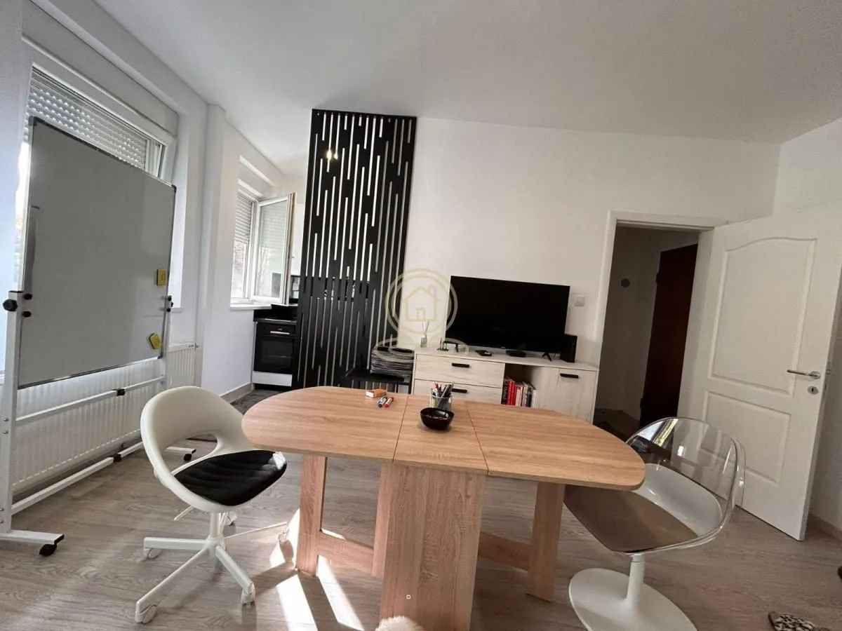 Living room with a dining table, TV unit, and decorative partition.