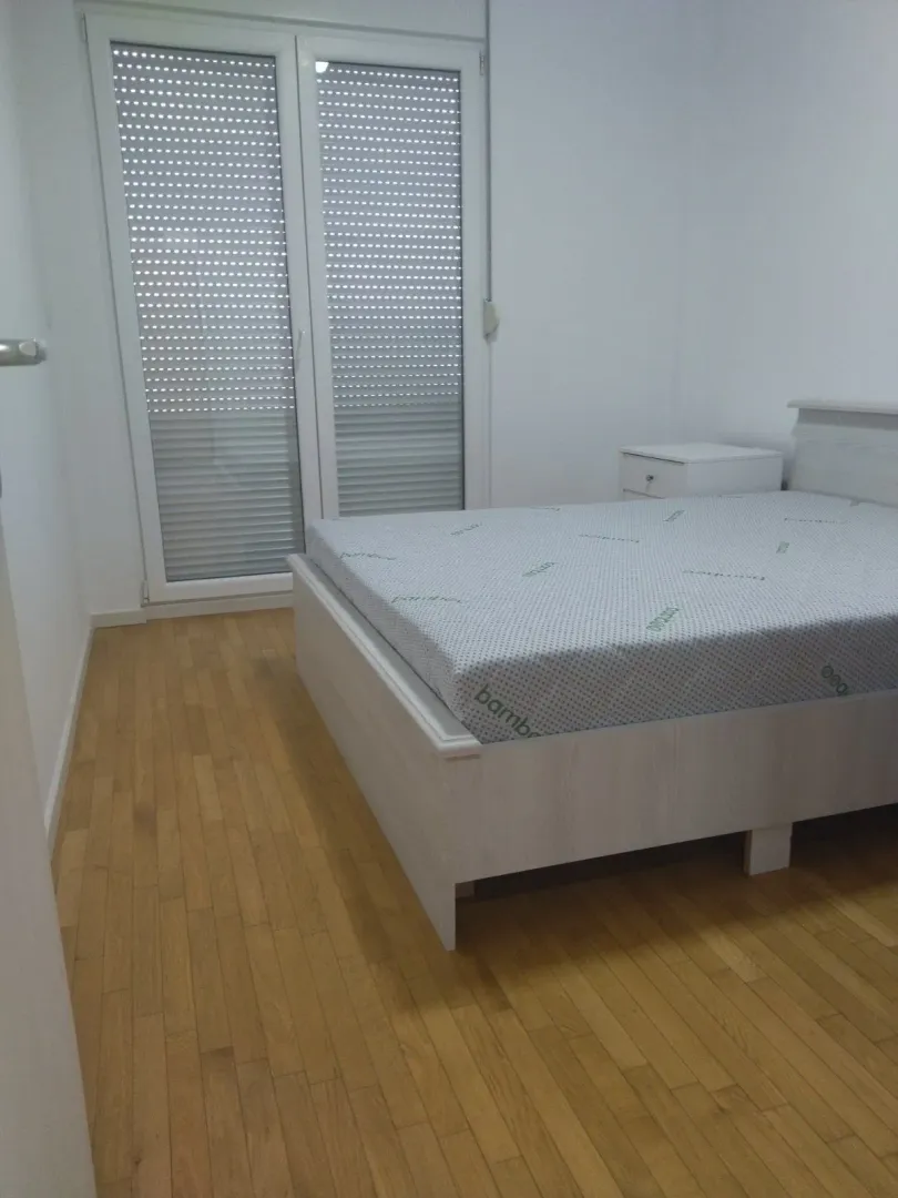 Svjetla spavaća soba sa bračnim krevetom i parketom.