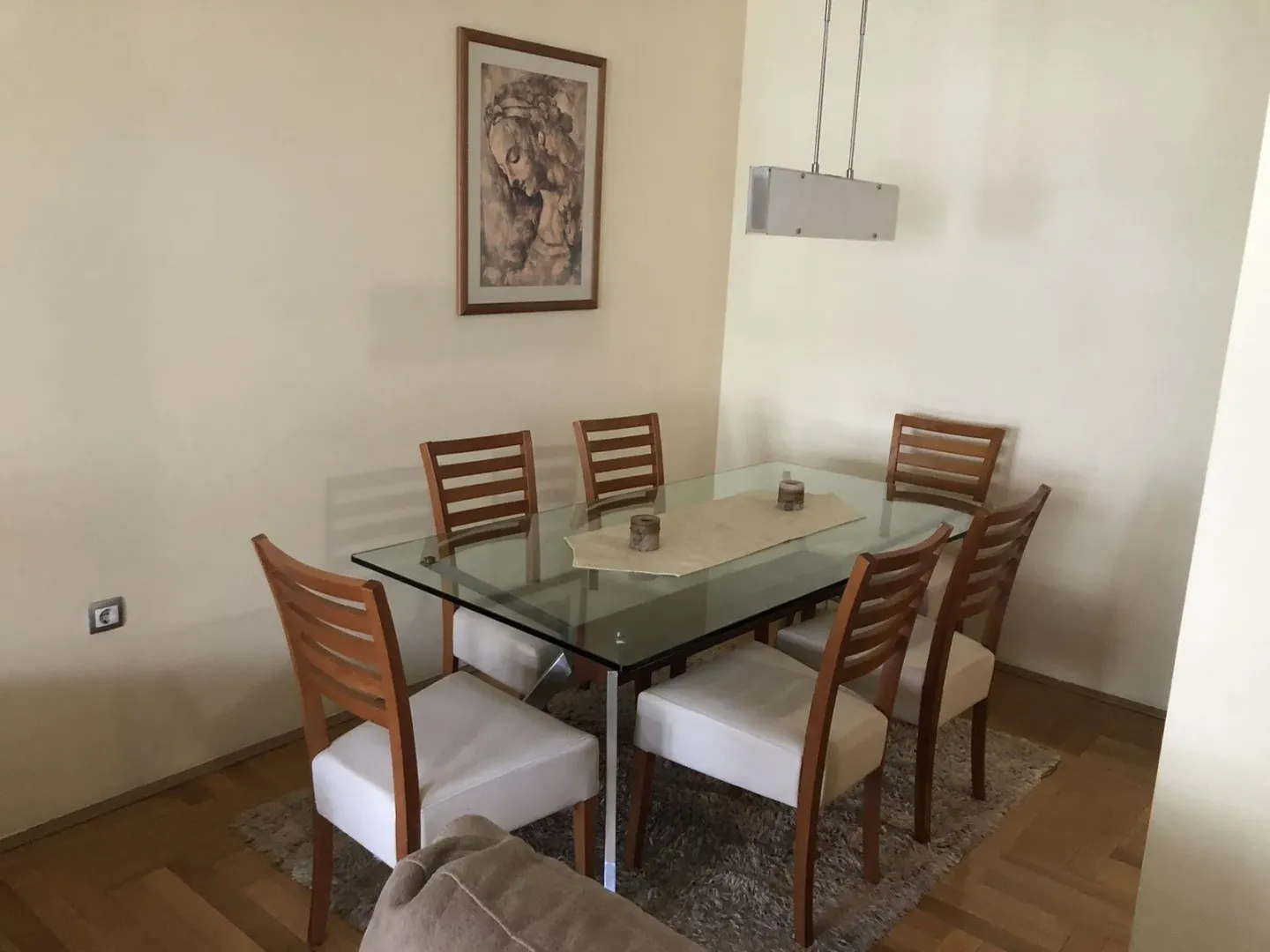 Dining area featuring a glass-top table and wooden chairs.