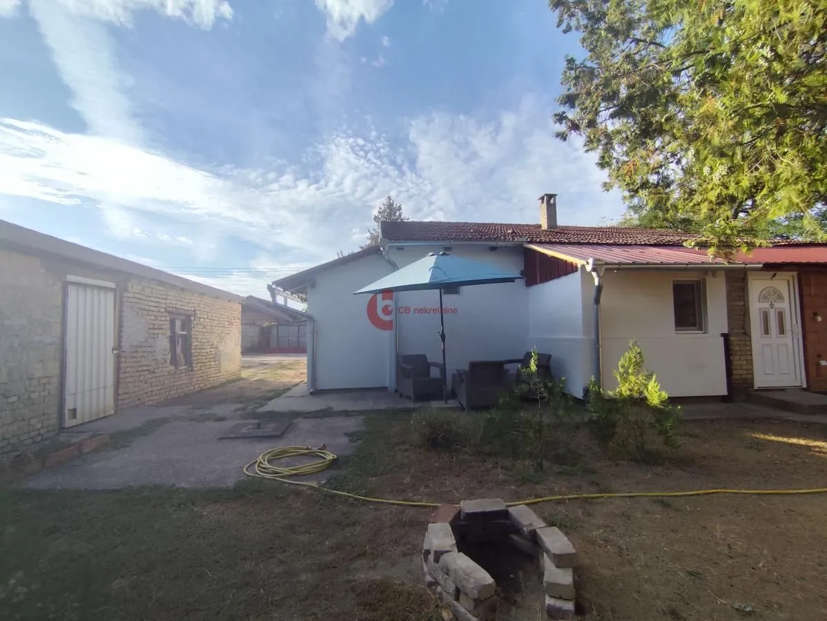 Pogled na dvorište i spoljašnjost kuće sa garniturom za sedenje.