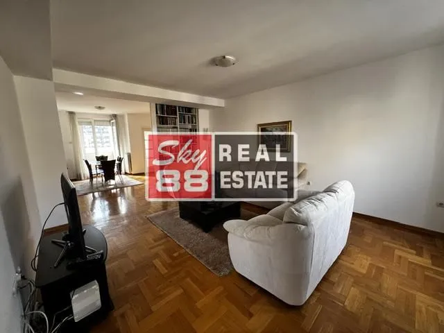 Dnevna soba sa garniturom i pogledom na trpezariju u pozadini.