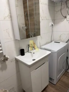 Bathroom with a sink, mirror, shower cabin, and washing machine. - image 8