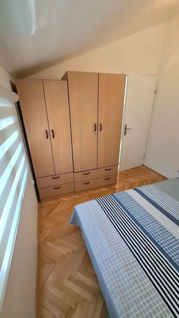 Bedroom with wooden wardrobes, bed, and parquet flooring.