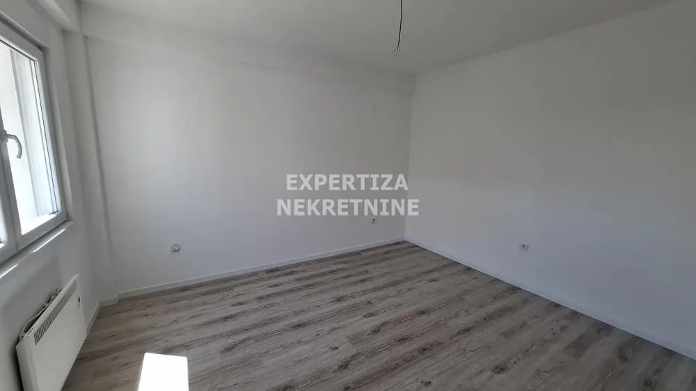 Empty room with white walls and laminate flooring.