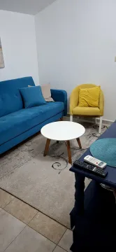 Living room with a blue sofa, yellow armchair, and round coffee table. - image 3