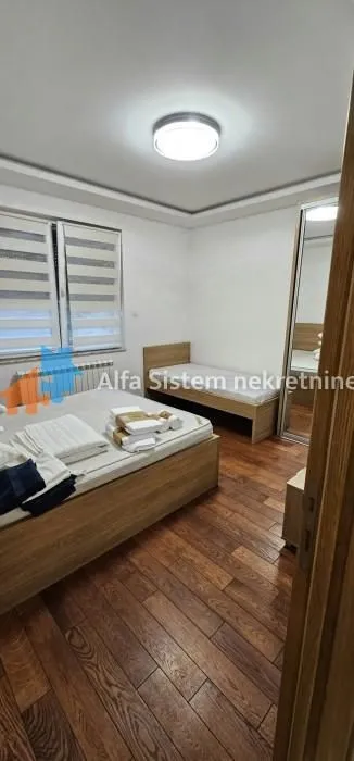 Spavaća soba sa dva kreveta, drvenim podom i velikim ormarom.