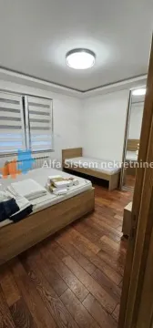 Spavaća soba sa dva kreveta, drvenim podom i velikim ormarom. - image 6
