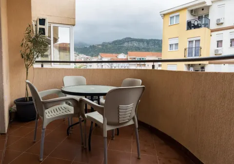 Furnished balcony with a table, chairs, and a view of surrounding buildings and hills. - image 3